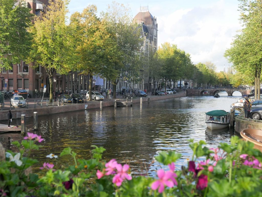 View on Keijzersgracht with some flowers in a foreground, small boat and canal houses