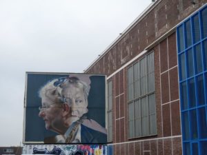 Industrial building with a mural showing two realistic portraits on it
