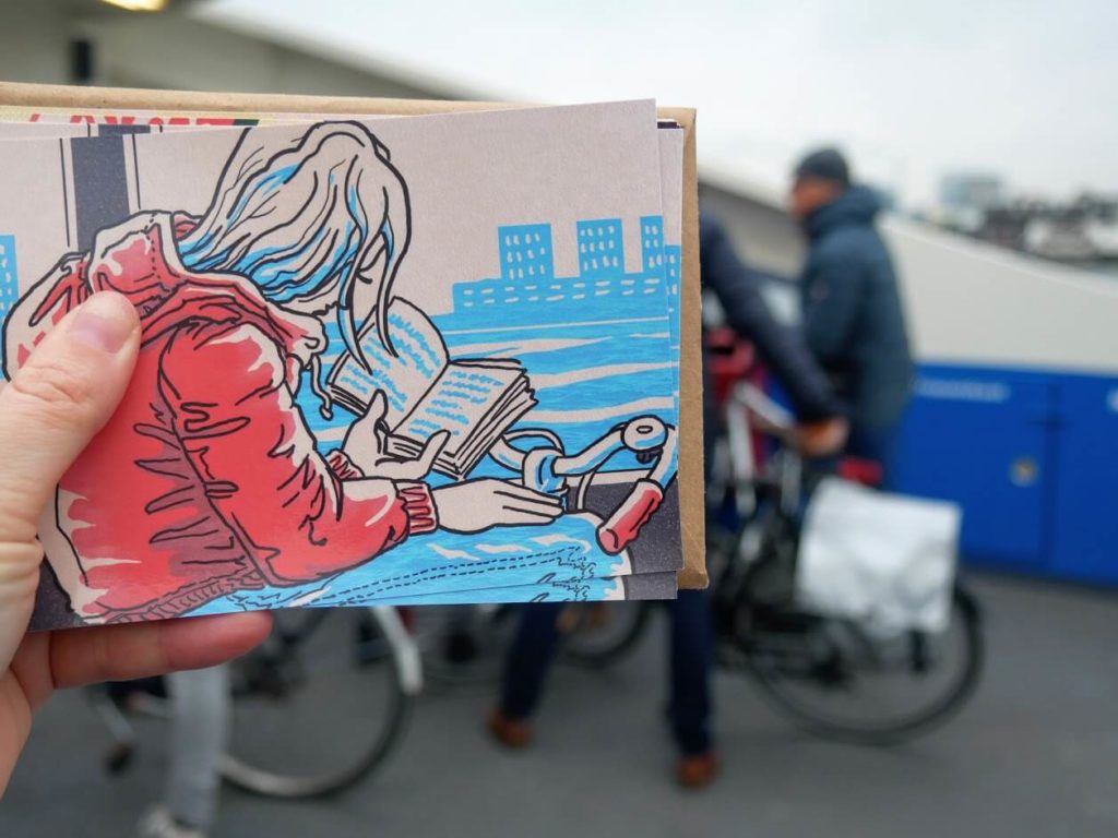 Tea holding one of Rachelle's illustrations on a ferry