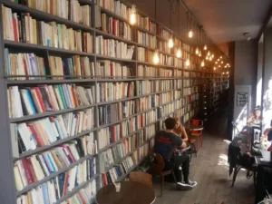 A couple sitting at a cafe next to the wall covered with books